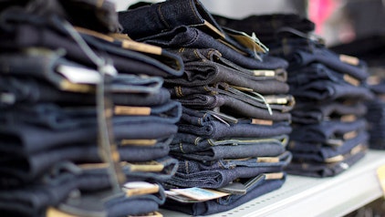 Viele dunkle Jeanshosen gestapelt in einem Regal